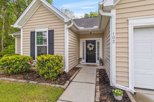 entrance to property with a shingled roof and a garage
