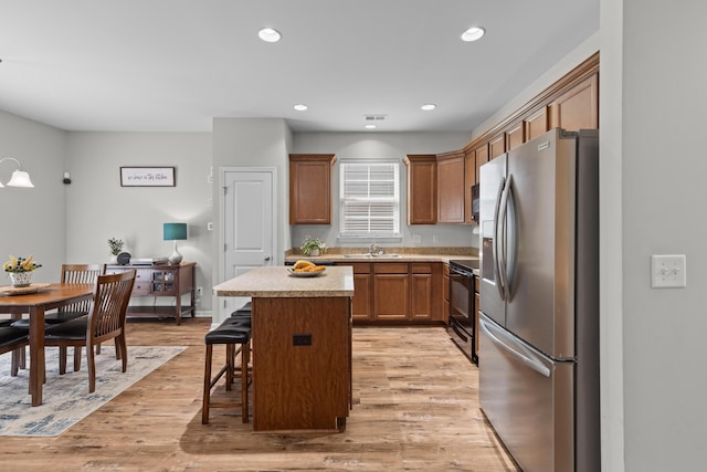 kitchen with a kitchen breakfast bar, stainless steel fridge, a kitchen island, light wood finished floors, and black range with electric stovetop