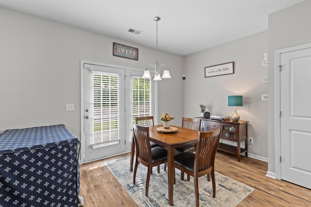 dining room with light wood-style flooring, baseboards, a notable chandelier, and visible vents
