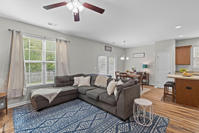 living room featuring light wood-style flooring, ceiling fan, baseboards, and a healthy amount of sunlight