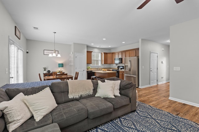 living room featuring visible vents, baseboards, light wood finished floors, recessed lighting, and ceiling fan with notable chandelier