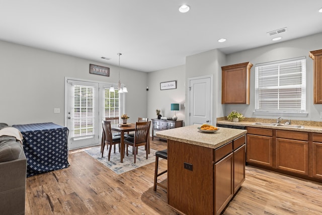 kitchen featuring open floor plan, a center island, a sink, and visible vents