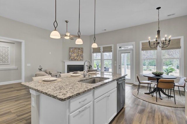 kitchen with sink, dishwasher, white cabinets, hanging light fixtures, and an island with sink