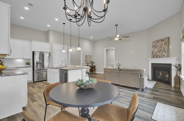 dining area featuring ceiling fan, sink, and dark wood-type flooring