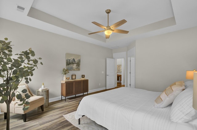 bedroom featuring a tray ceiling, ceiling fan, and wood-type flooring