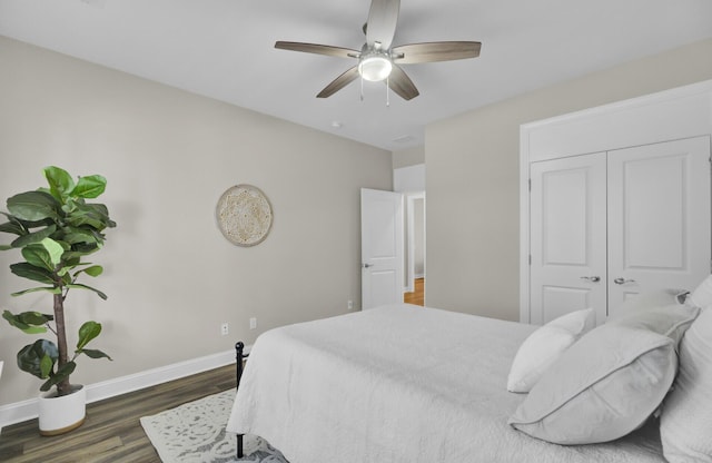 bedroom with ceiling fan, dark wood-type flooring, and a closet