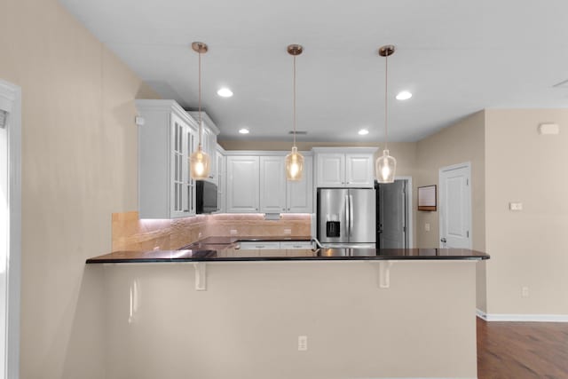 kitchen featuring white cabinets, stainless steel refrigerator with ice dispenser, hanging light fixtures, dark hardwood / wood-style floors, and kitchen peninsula