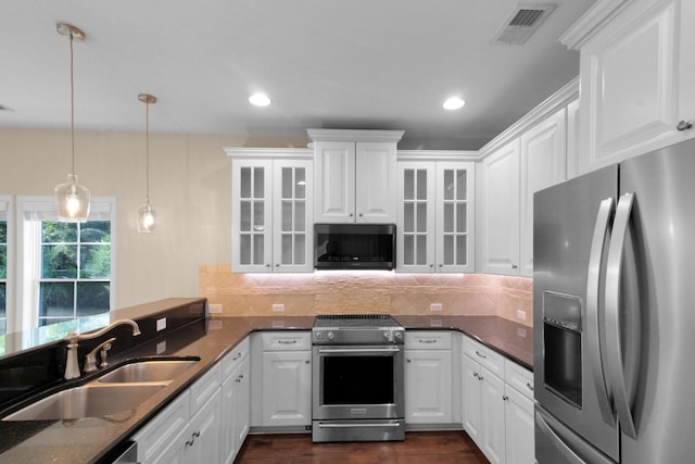 kitchen featuring white cabinets, hanging light fixtures, and appliances with stainless steel finishes