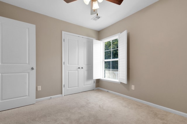 unfurnished bedroom featuring ceiling fan, light carpet, and a closet