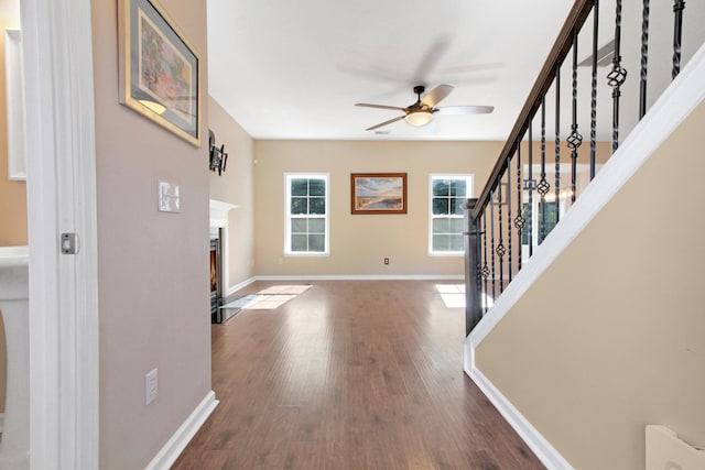 unfurnished living room featuring ceiling fan and dark wood-type flooring