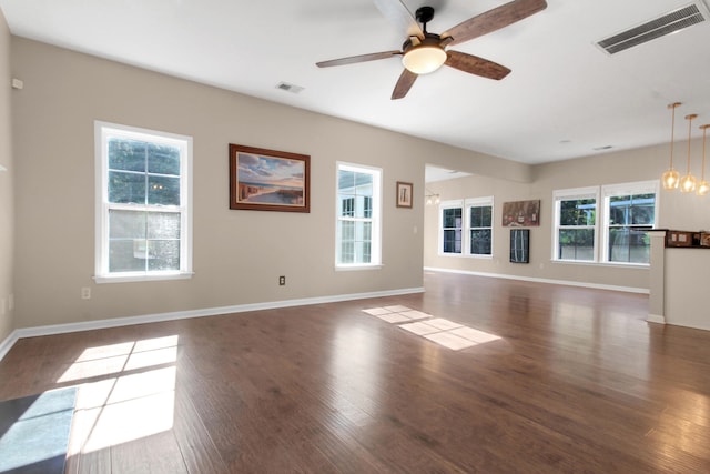 unfurnished living room with dark hardwood / wood-style flooring and ceiling fan with notable chandelier