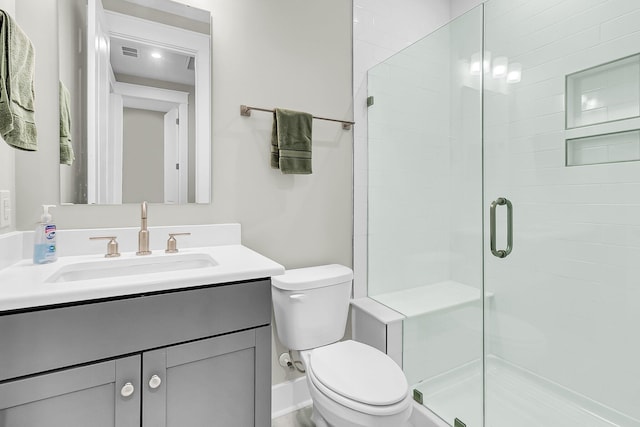 bathroom featuring vanity, an enclosed shower, and toilet