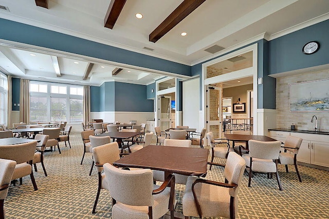 dining area with sink, beam ceiling, crown molding, and light carpet