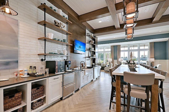 kitchen featuring coffered ceiling, a kitchen breakfast bar, white cabinets, beamed ceiling, and light parquet flooring