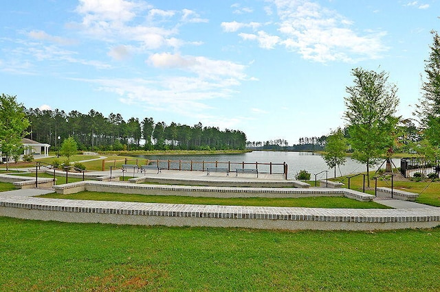 view of home's community with a water view, a dock, and a lawn