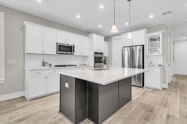 kitchen with a center island with sink, white cabinetry, sink, and appliances with stainless steel finishes