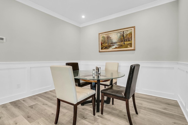 dining area with light wood-type flooring and ornamental molding