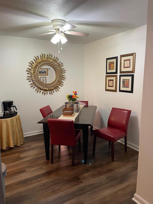 dining space featuring dark wood-type flooring, a textured ceiling, and ceiling fan