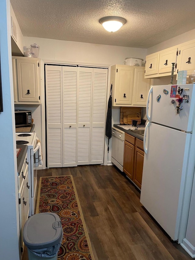 kitchen featuring white appliances, white cabinetry, a textured ceiling, and dark hardwood / wood-style floors