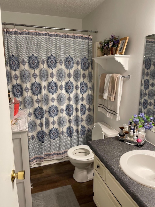 bathroom with a textured ceiling, wood-type flooring, toilet, vanity, and a shower with curtain