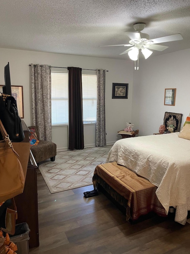 bedroom with ceiling fan, wood-type flooring, and a textured ceiling