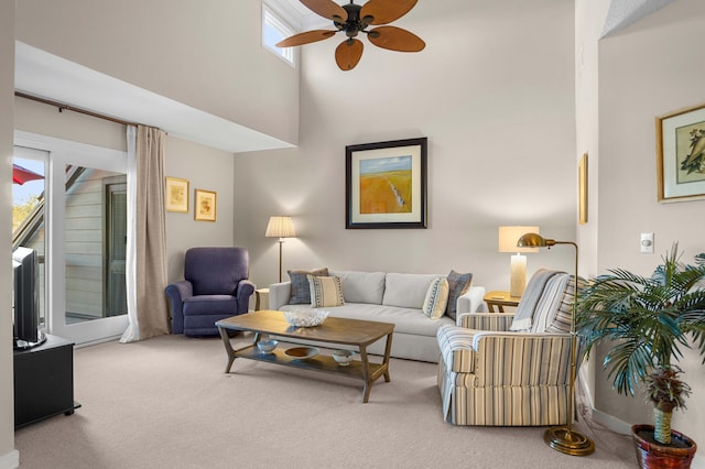 carpeted living area with ceiling fan and a towering ceiling