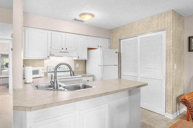 kitchen featuring under cabinet range hood, light countertops, a peninsula, white appliances, and a sink