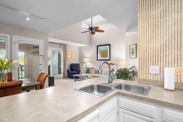 kitchen featuring a sink, white cabinetry, open floor plan, and light countertops