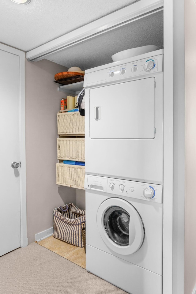 clothes washing area with laundry area, stacked washer / dryer, carpet flooring, and a textured ceiling