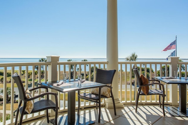 balcony with outdoor dining space and a water view