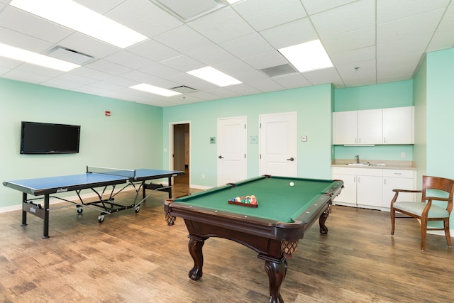 rec room featuring baseboards, wood finished floors, visible vents, and a sink