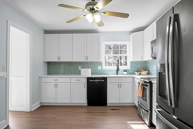 kitchen with stainless steel appliances, a sink, white cabinets, light wood-style floors, and light countertops