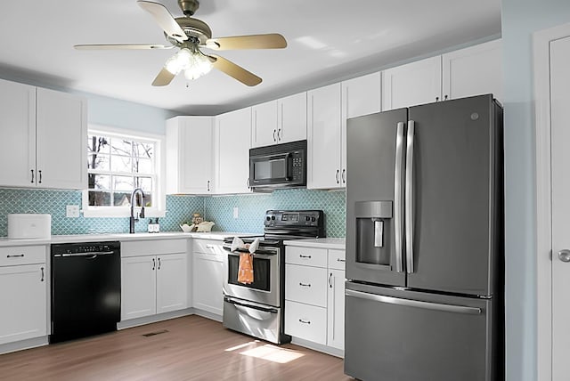 kitchen with tasteful backsplash, light wood-style flooring, black appliances, white cabinetry, and a sink