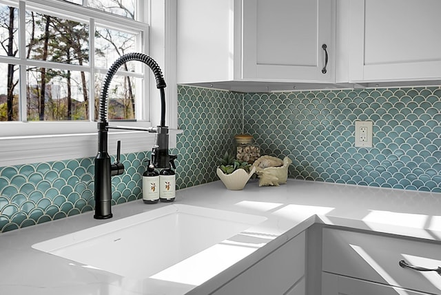 details with white cabinets, light countertops, a sink, and decorative backsplash