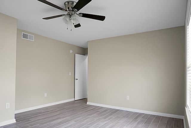 spare room with ceiling fan, wood finished floors, visible vents, and baseboards