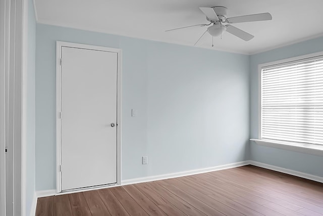 unfurnished room with a ceiling fan, baseboards, and wood finished floors