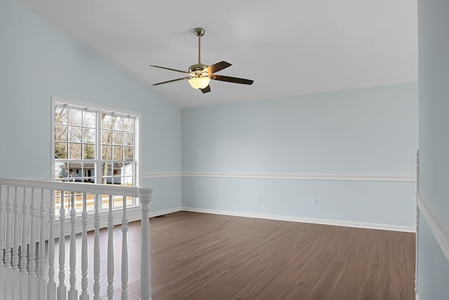 unfurnished room featuring lofted ceiling, dark wood-style floors, baseboards, and a ceiling fan