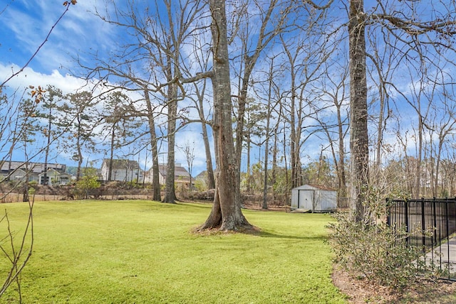 view of yard featuring an outbuilding, fence, and a shed