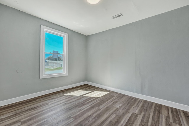 unfurnished room featuring visible vents, baseboards, and wood finished floors