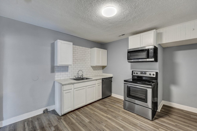 kitchen with visible vents, stainless steel appliances, light wood-type flooring, white cabinetry, and a sink