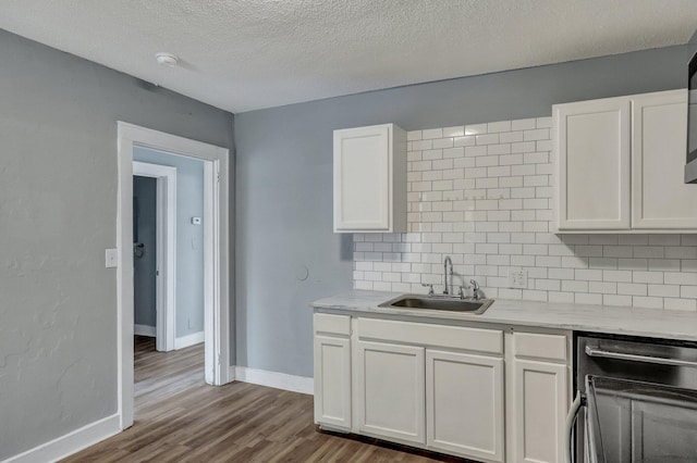 kitchen featuring white cabinets, tasteful backsplash, light countertops, and a sink