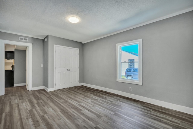 unfurnished bedroom featuring a closet, wood finished floors, visible vents, and baseboards