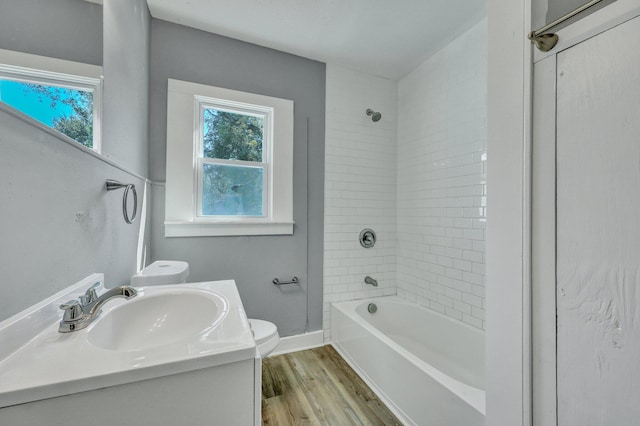 bathroom with baseboards, toilet, wood finished floors, vanity, and washtub / shower combination