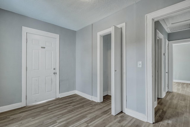 interior space featuring visible vents, a textured ceiling, baseboards, and wood finished floors