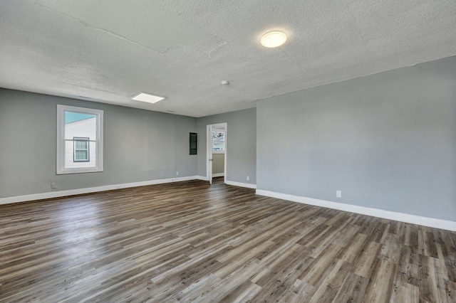 spare room featuring a textured ceiling, wood finished floors, and baseboards