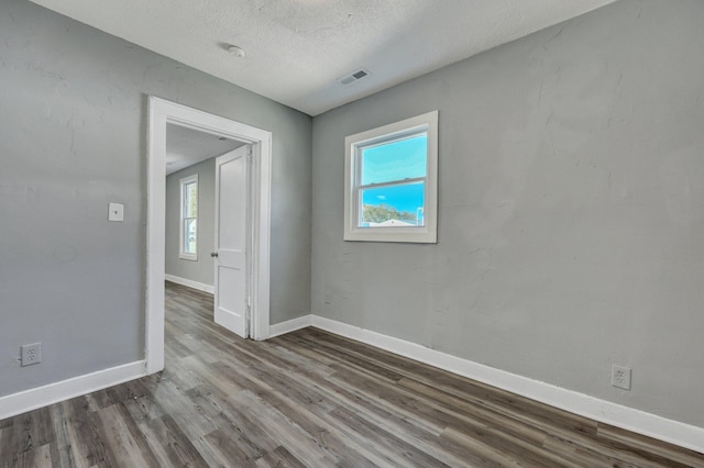 empty room with a healthy amount of sunlight, visible vents, baseboards, and wood finished floors