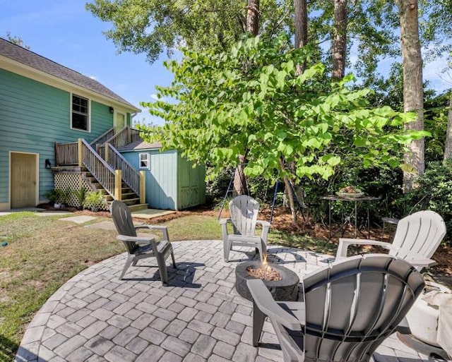 view of patio featuring a storage shed, a wooden deck, and a fire pit