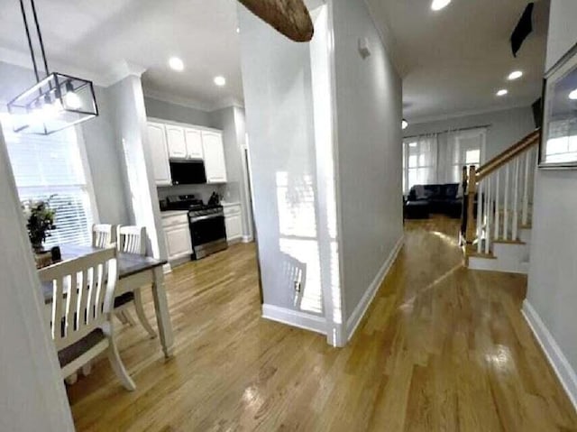 hall featuring plenty of natural light, ornamental molding, and light hardwood / wood-style floors