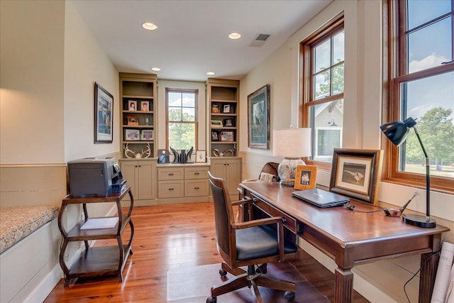 office featuring wood-type flooring, a wealth of natural light, and built in shelves