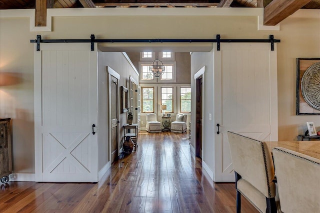 interior space featuring a barn door, dark hardwood / wood-style flooring, and beamed ceiling